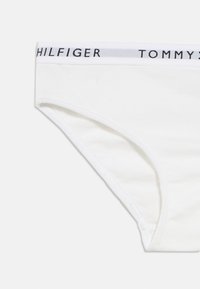 Valged puuvillased aluspüksid musta ja halli logoga vöökohaga, millel on sile tekstuur ja klassikaline lõige.