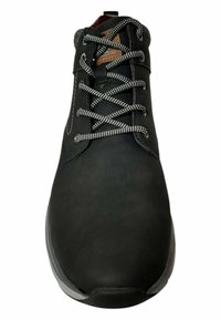 Zapato de cuero negro con superficie texturizada, puntera redonda, cordones blancos en contraste y detalles de cuero marrón en la lengüeta.