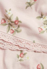 Stoff mit Blumenmuster, der Erdbeeren und weißen Blumen auf einem sanften rosa Hintergrund zeigt. Verfügt am Rand über eine zarte Spitzenverzierung.