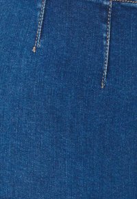 Stof de denim de culoare albastru închis, cu o textură netedă, având un fermoar frontal și închidere cu buton, precum și detalii subtile de cusătură pe marginile cusăturilor.