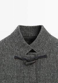 Cappotto grigio in misto lana con tessuto strutturato, collo sagomato e chiusura a moschettone con dettagli in corda nera.