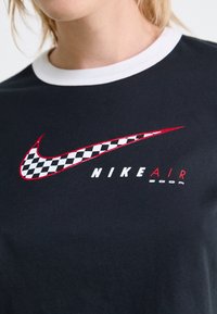 Černé bavlněné tričko s bílým žebrovaným límečkem, červeným a kostkovaným logem Nike swoosh a textem "NIKE AIR ZOOM" v bílé a červené barvě.