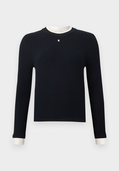 Μαύρο ριμπ πλεκτό πουλόβερ με μακριά μανίκια, λευκή στρογγυλή λαιμόκοψη και μανσέτες, με μικρή τετράγωνη διακοσμητική λεπτομέρεια στο κέντρο του στήθους.