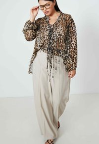 Leopard print, semi-doorlatende blouse met een trekkoordhals, lange mouwen en een relaxte pasvorm, gecombineerd met beige wijde pantalon.