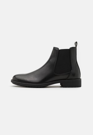 Sort læder Chelsea-støvle med elastisk sidepanel, lav blokhæl og trækskede bagpå, vist i profil mod hvid baggrund.