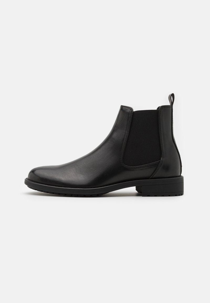 Bottine Chelsea noire en cuir avec panneau latéral élastique, talon bloc bas et languette à l'arrière, vue de profil sur fond blanc.