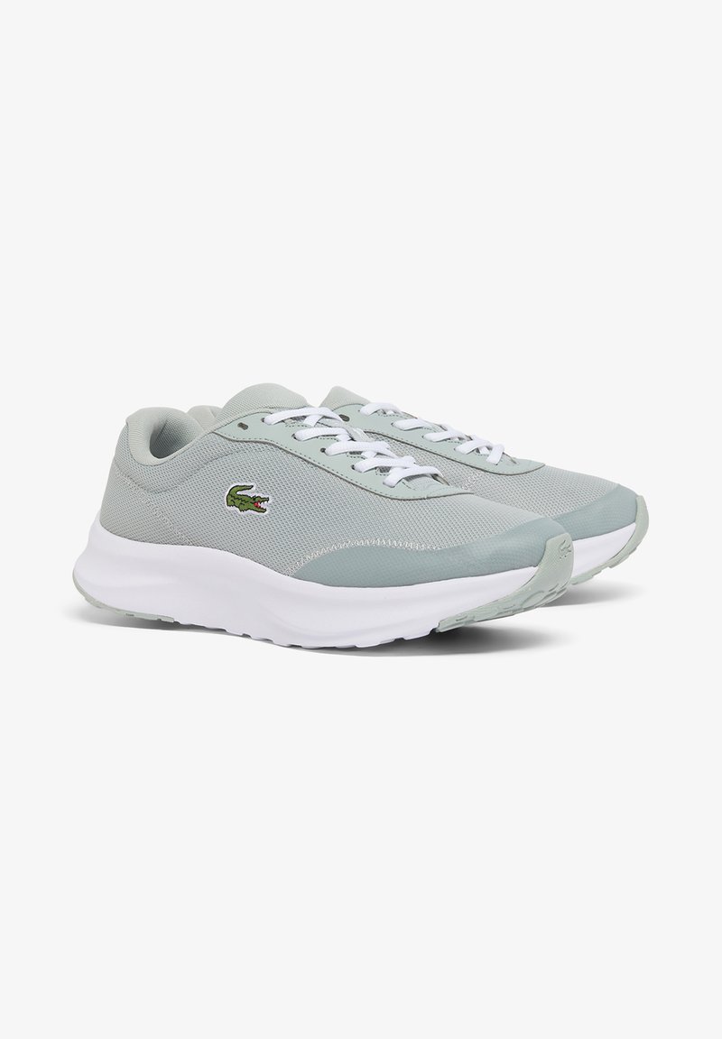 Chaussures de sport en mesh gris clair avec semelles et lacets blancs, arborant un logo crocodile vert sur le côté.