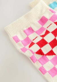 Två par färgglada mönstrade strumpor med ett rutigt mönster i rosa, röd och vit, uppvisade mot en ljus bakgrund.