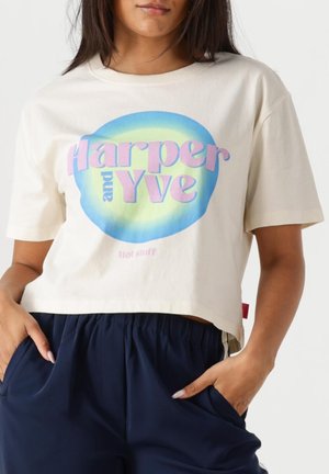 Crème-kleurige cropped t-shirt met een blauwe en groene cirkelvormige grafiek met de tekst "Harper and Yve" in het roze en "Hot stuff" daaronder.