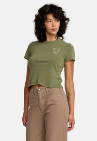 Oliwkowy krótki t-shirt z miękkiego materiału, z krótkimi rękawami, z białą grafiką podkowy na lewej części klatki piersiowej.