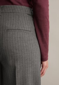 Szare spodnie w prążek z tylną kieszenią, zestawione z bordową koszulą z długim rękawem. Tkanina ma gładką teksturę i dopasowany krój.