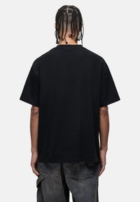 Zwarte katoenen t-shirt met ronde hals, losse pasvorm en korte mouwen. Heeft een gladde textuur en een rechte zoom, zonder zichtbare patronen of accenten.