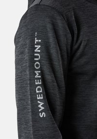 Maglietta sportiva grigia a maniche lunghe con un tessuto testurizzato, con "SWEDEMOUNT" stampato verticalmente sulla manica sinistra in lettere bianche.