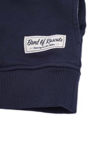 Marinblå sweatshirtärm med ribbad struktur, med en vit etikett som läser "Band of Rascals" och frasen "Finest Organic Kids Clothes."