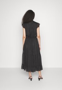 Robe maxi noire avec un design à volants, manches courtes volantées, taille élastique et texture rayée subtile.