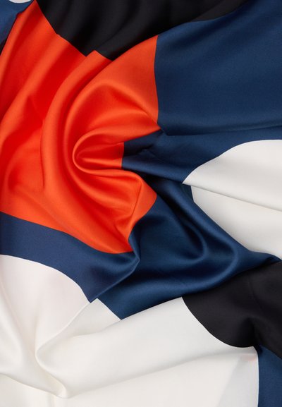 Jedwabista tkanina o mieszance wyrazistych kolorów: pomarańczowego, granatowego, czarnego i białego, o gładkiej teksturze i wzorach zaokrąglonych kształtów.