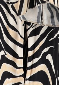 Tela a rayas de cebra en negro y crema con una textura suave, que presenta un borde rizado y sutiles acentos beige en el diseño.
