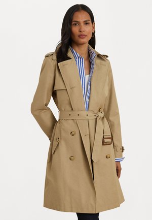 Trench coat beige con design doppiopetto, vita con cintura e spalline. Presenta una texture liscia e una camicia a righe abbinata sotto.