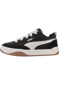 Sneaker bianco e nero con tessuto testurizzato, dettagli in suede e una suola in gomma marrone. Presenta lacci bianchi e un logo sul lato.