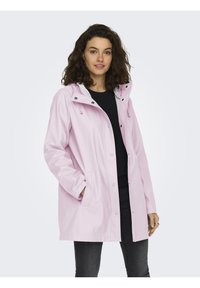 Chaqueta impermeable rosa con capucha, botones a presión y bolsillos laterales. Textura suave, diseño de longitud media y forro interior en contraste.