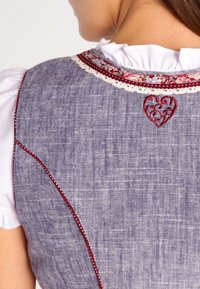 Tenue traditionnelle en lin bleu, ornée d'un cœur rouge brodé décoratif et d'une bordure florale le long de l'encolure.