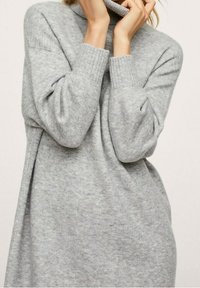 Pull en maille grise avec un col montant, des poignets côtelés et une coupe décontractée. Texture douce et finition lisse, adapté pour un superposition décontractée.