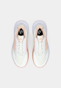 Scarpe da ginnastica bianche con dettagli e lacci color pesca, viste dall'alto su uno sfondo bianco uniforme.