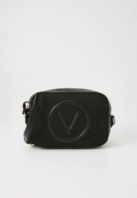 Bolsa tiracolo retangular preta feita de material texturizado, com um logótipo circular proeminente com um "V" no centro e uma alça ajustável.