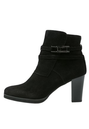 Bottine en suède noir avec un accent de boucle sur le côté, talon haut et bout arrondi. Possède une texture lisse et un design ajusté.