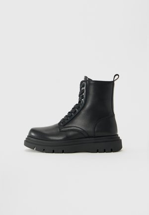 Black leather ankle boot with thick sole, lace-up front, and pull tab at heel on a plain white background.