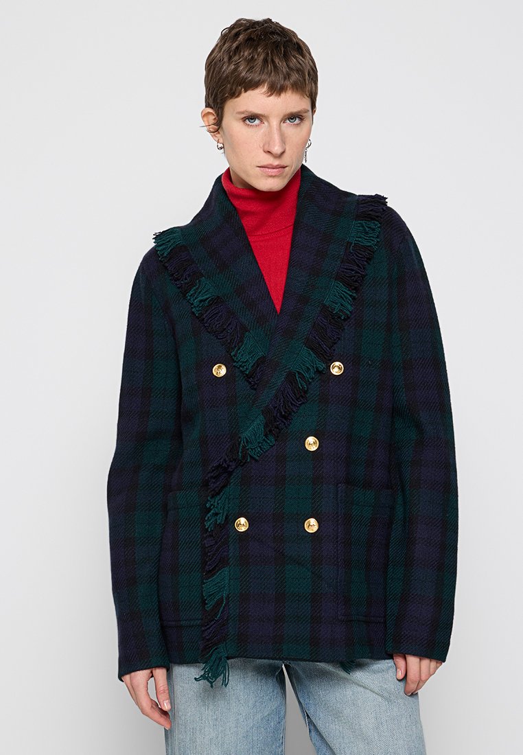 Dwurzędowy płaszcz w kratę w ciemnozielonym i granatowym kolorze z złotymi guzikami, z frędzlami wzdłuż kołnierza i przodu.