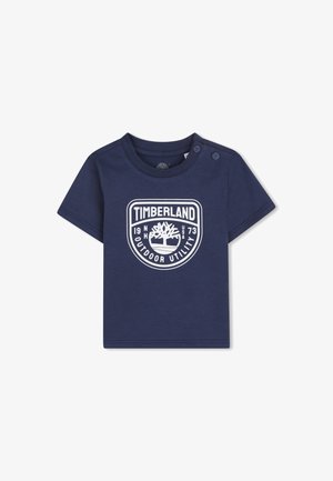 Marineblauw peuter T-shirt met Timberland-logo en tekst "Outdoor Utility", met twee knopen op de linkerschouder voor gemakkelijk aan- en uittrekken.