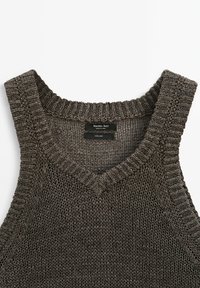 V-výstřih lněná tank top v tmavě šedé barvě s texturovaným pleteným vzorem a ribovými okraji. Odevní štítek na vnitřní straně výstřihu.