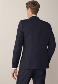Marinblå kostym med en skräddarsydd passform, utrustad med en enkel vent bak och ärmar med tre knappar, designad i ett mjukt tyg med en subtil lyster.