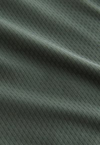 Gros plan d'un tissu vert avec une texture côtelée verticale subtile et des plis doux.