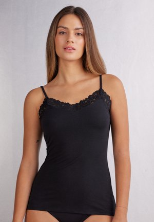 Zwarte camisole gemaakt van zachte stof met kantafwerking langs de halslijn en verstelbare dunne bandjes, die nauwsluitend op het lichaam zit.