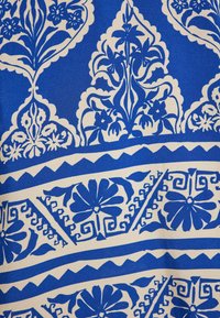 Țesătură cu un model albastru și alb, având designuri florale, motive răsucite elaborate și margini geometrice, cu o textură netedă.