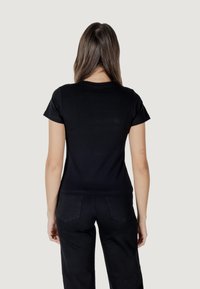 Zwarte fitted t-shirt met korte mouwen, ronde hals, gladde katoen stof, minimalistisch design, gedragen met hoge taille zwarte broek.