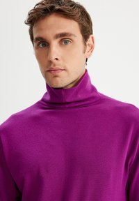 Fioletowy sweter z wysokim kołnierzem, wykonany z dzianiny o miękkiej teksturze, z luźnym krojem. Minimalistyczny design.