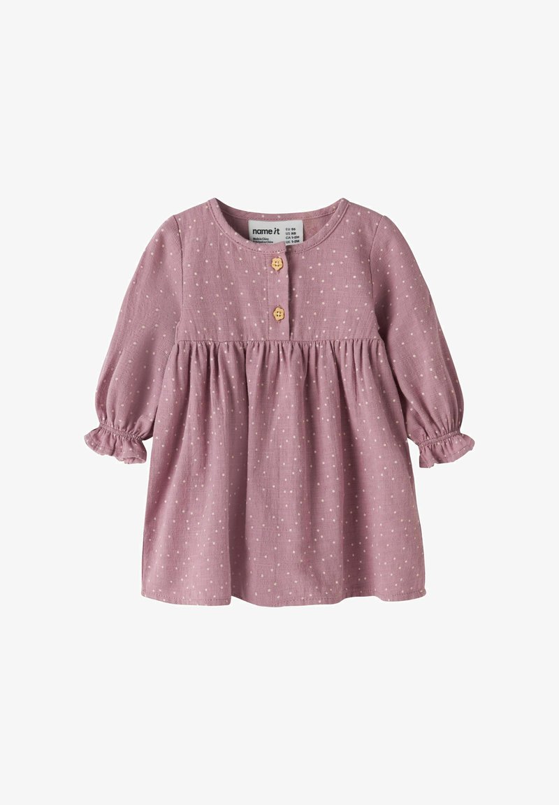 Robe bébé rose à manches longues avec des pois blancs, deux boutons en bois sur le devant et des poignets élastiques aux manches.