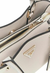 Sac à main beige clair en cuir texturé, matériel doré, compartiments zippés doubles et accents noirs. Présente une plaque logo triangulaire.