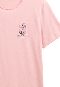 Camiseta de manga corta rosa hecha de tela suave, con un gráfico en azul marino de una bebida con lima y hojas, y el texto "HAVANA TIMES."