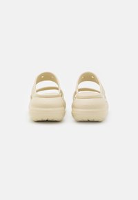 Crocs beige con apertura posteriore e due cinghie superiori. Texture liscia, design leggero e motivo a rilievo sulla suola.