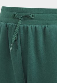 Pantalones cortos verdes con cinturilla elástica y detalle de cordón. Hechos de una tela suave y texturizada, con costuras fruncidas para un ajuste relajado.
