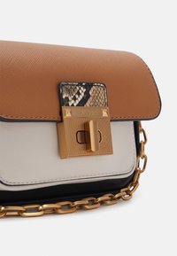 Tan and white color-blocked handbag with a gold lock closure, chain strap, and snake print accent on the flap. Made from textured materials.