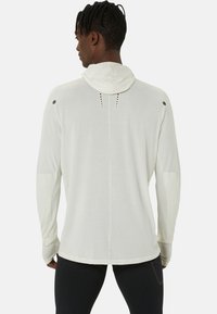 Lichtgrijze hoodie met lange mouwen, met een trekkoord, een textuurstof en geperforeerde details op de rug en schouders.