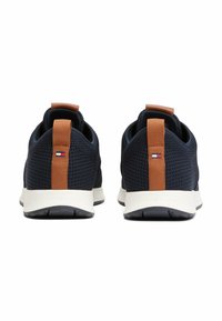 Zapatillas de malla azul con una lengüeta de cuero marrón, suelas blancas y un pequeño logo en la parte posterior. Superficie texturizada para transpirabilidad.