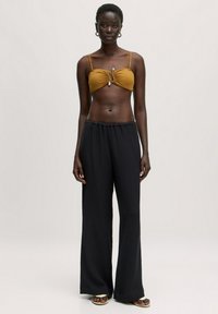 Bronzen bikini-top met geplooid ontwerp en zilverkleurige accenten, gecombineerd met zwarte, wijde, gestructureerde broek. Eenvoudige en functionele stijl.