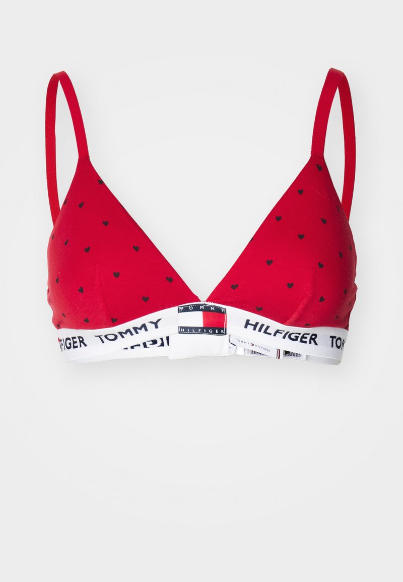 Bralette triangulaire rouge avec de petits motifs de cœurs noirs, fines bretelles, et une bande blanche arborant le logo "Tommy Hilfiger".