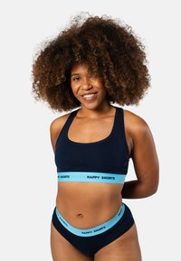 Ensemble de brassière de sport marine et de sous-vêtements assortis avec des bandes élastiques bleu clair présentant le texte "HAPPY SHORTS", fabriqué à partir d'un tissu doux et extensible.